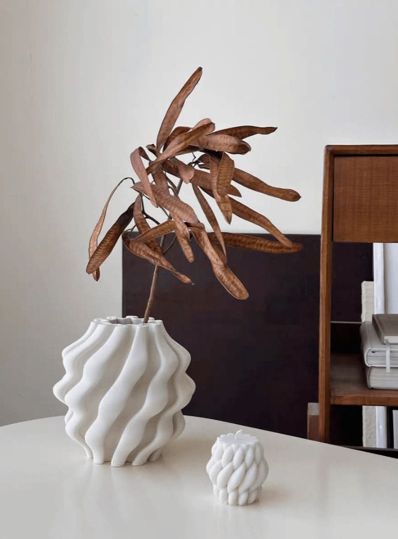 White 3D printed vase for plants with wavy texture, holding dried seed pods. Home decor.